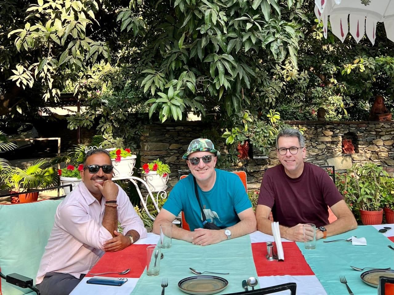 Three men seated at an outdoor table talking through a printed itinerary and map