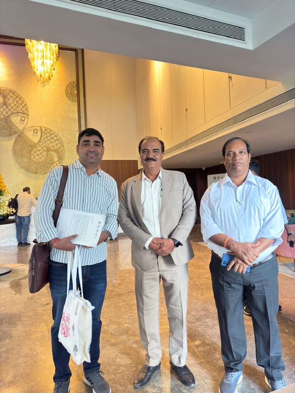 A guest holding trip documents in a hotel lobby with two staff members