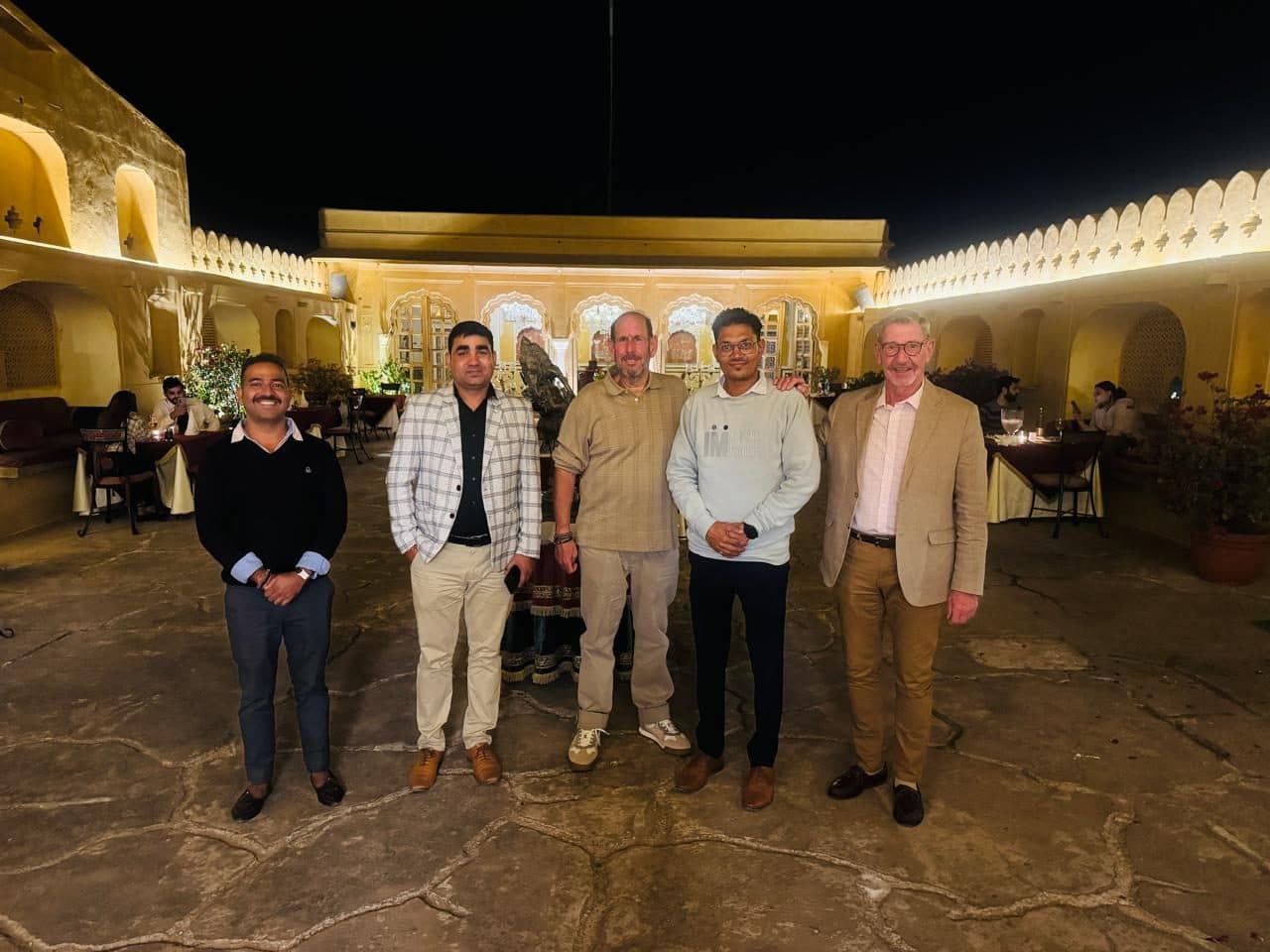 A group of guests and staff standing together in a lit heritage-hotel courtyard at night