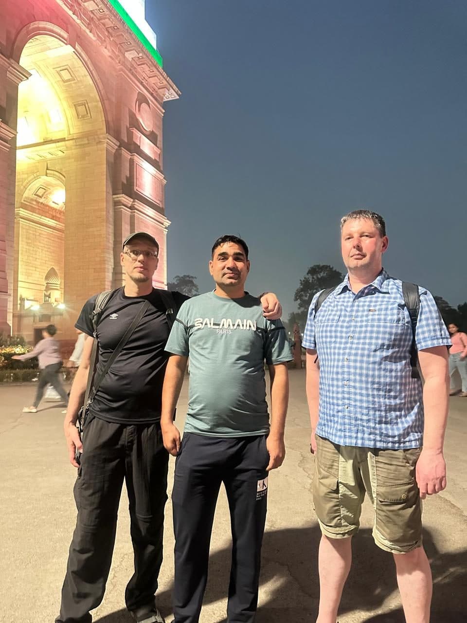 A guide and three guests photographed outside a lit monument on one of the last evenings