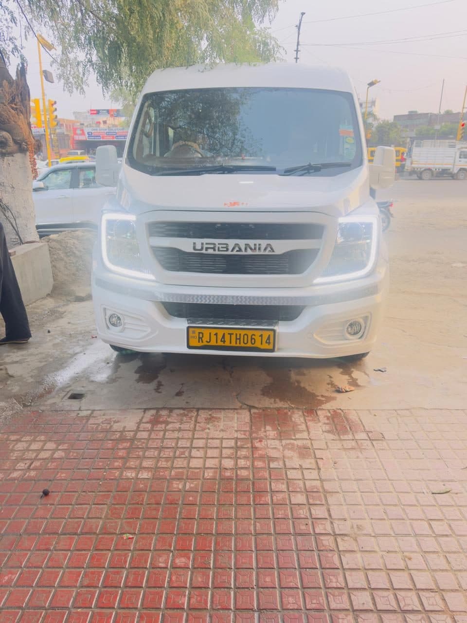 A white Force Urbania coach with a marigold garland across its grille on the first morning
