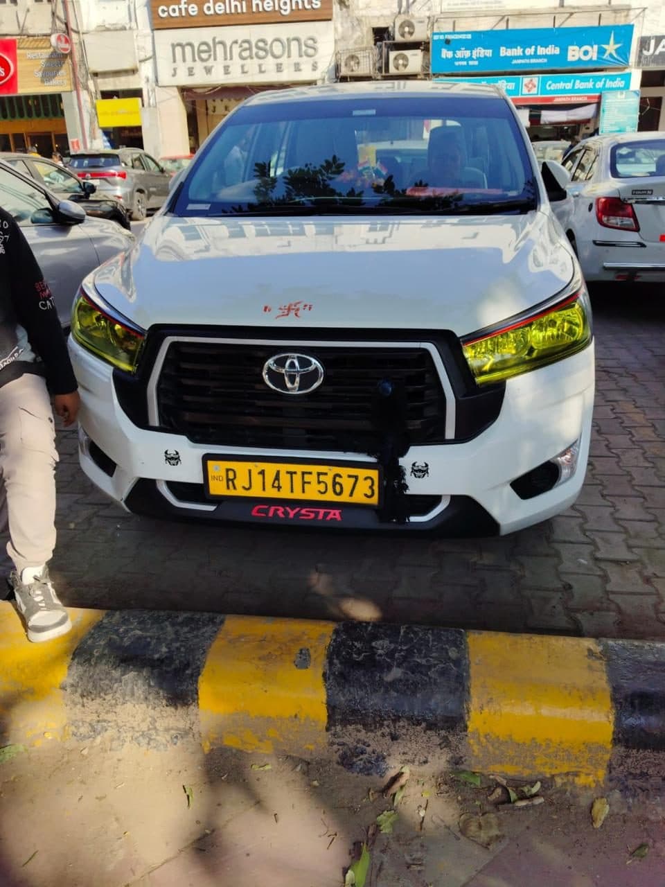 A white Toyota Hilux pickup on a city street, used to carry the group's luggage