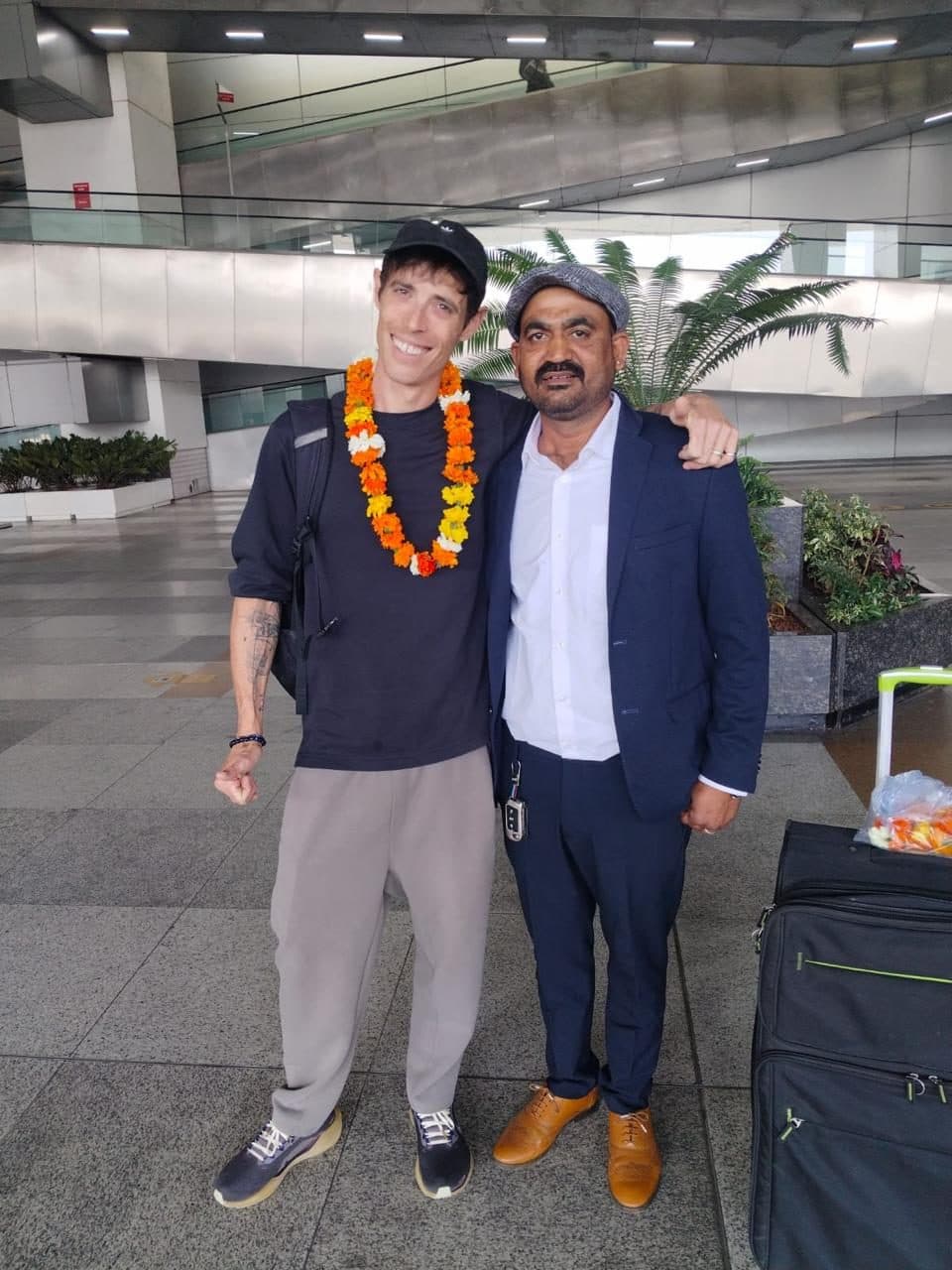 A chauffeur and his guest, both garlanded, standing beside the coach before setting off