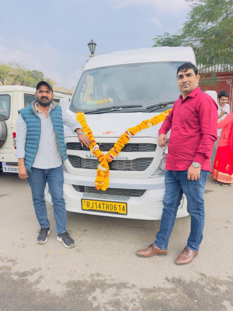 A driver and a guest standing beside a garlanded white coach