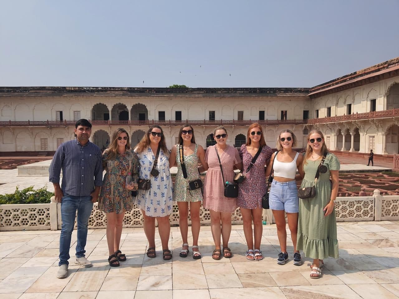 A group of guests posing together in a red-sandstone fort courtyard in Agra