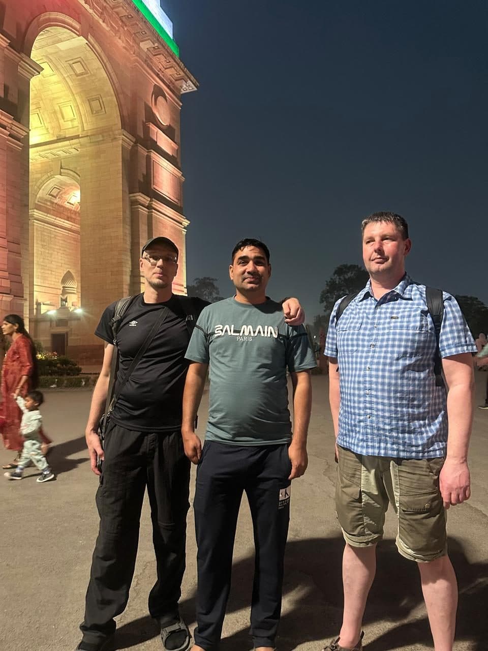 Three guests photographed at dusk in front of a domed Mughal monument in Old Delhi