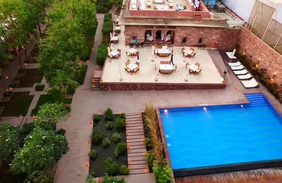 An aerial view of a heritage hotel's pool terrace set among clipped gardens