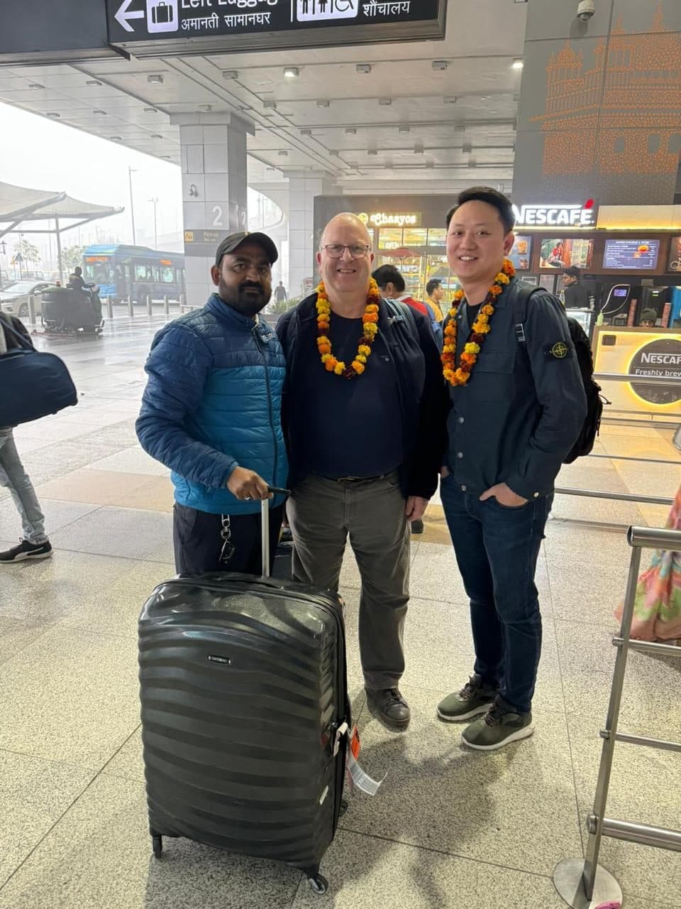 Guests and their guide with marigold garlands and luggage after a late-evening landing