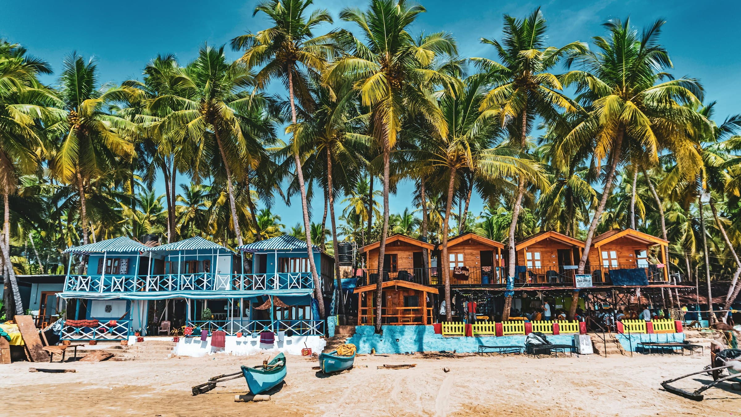 Colorful beach huts and palm trees along the sand at Palolem Beach, Goa