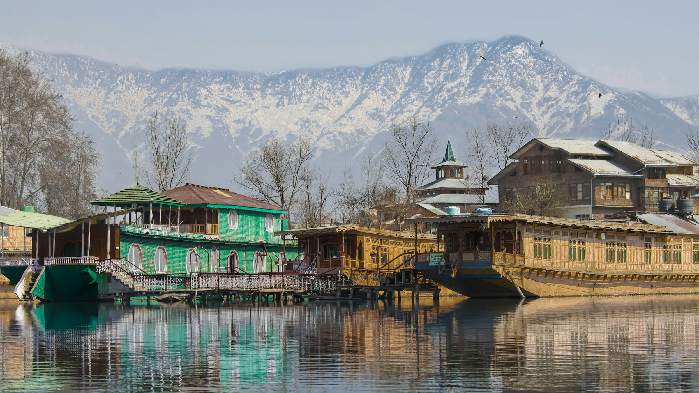 Wooden houseboats moored on Dal Lake in Srinagar, Kashmir, with mountains behind