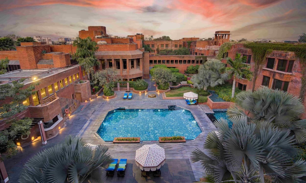ITC Mughal's outdoor swimming pool at dusk, framed by the resort's red sandstone architecture