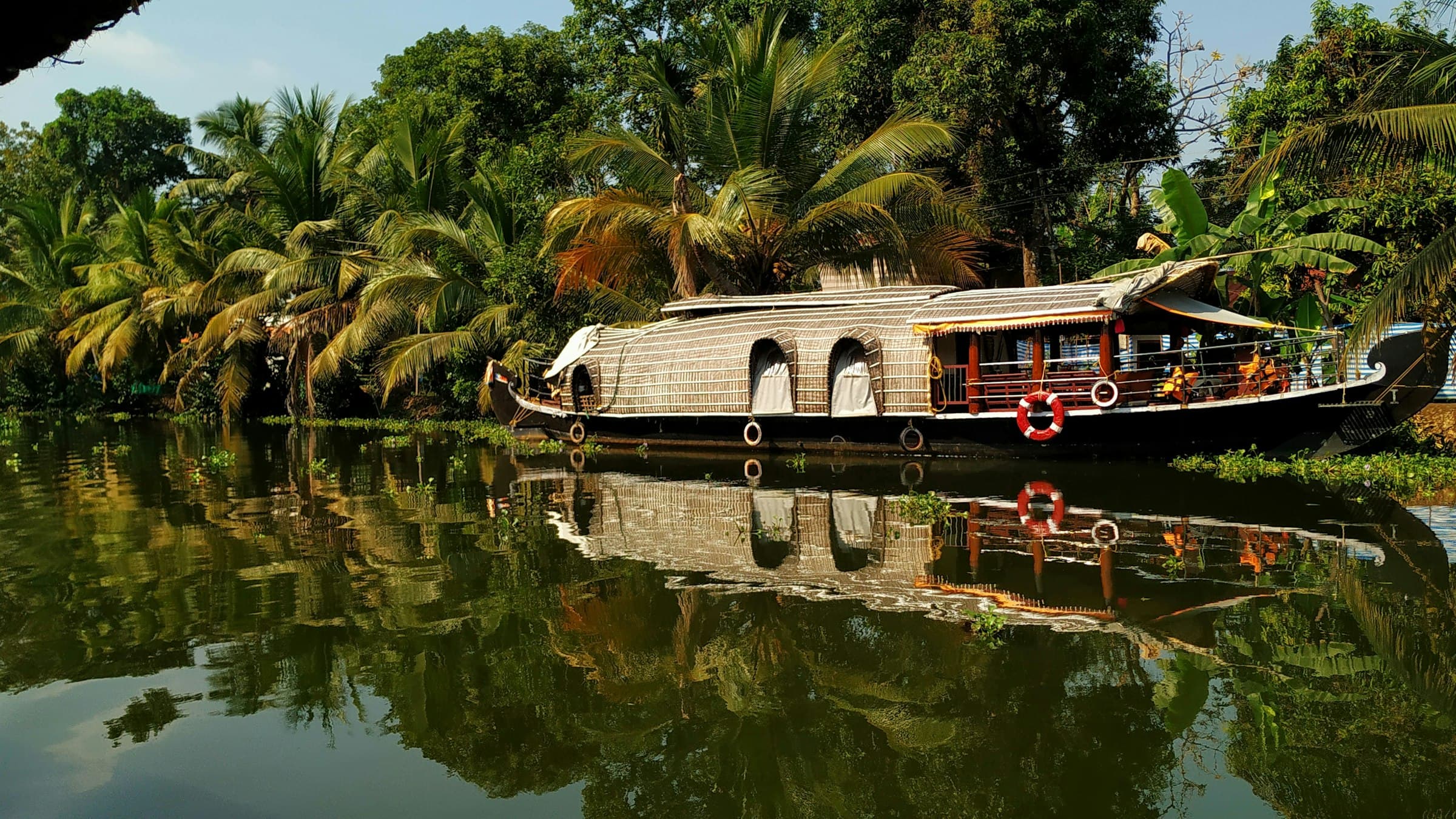 A houseboat on a palm-lined backwater river near Kumarakom