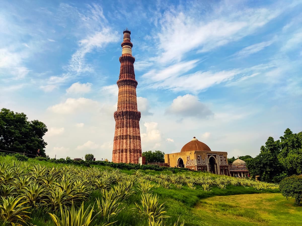 The Qutub Minar rising above its complex under a bright sky