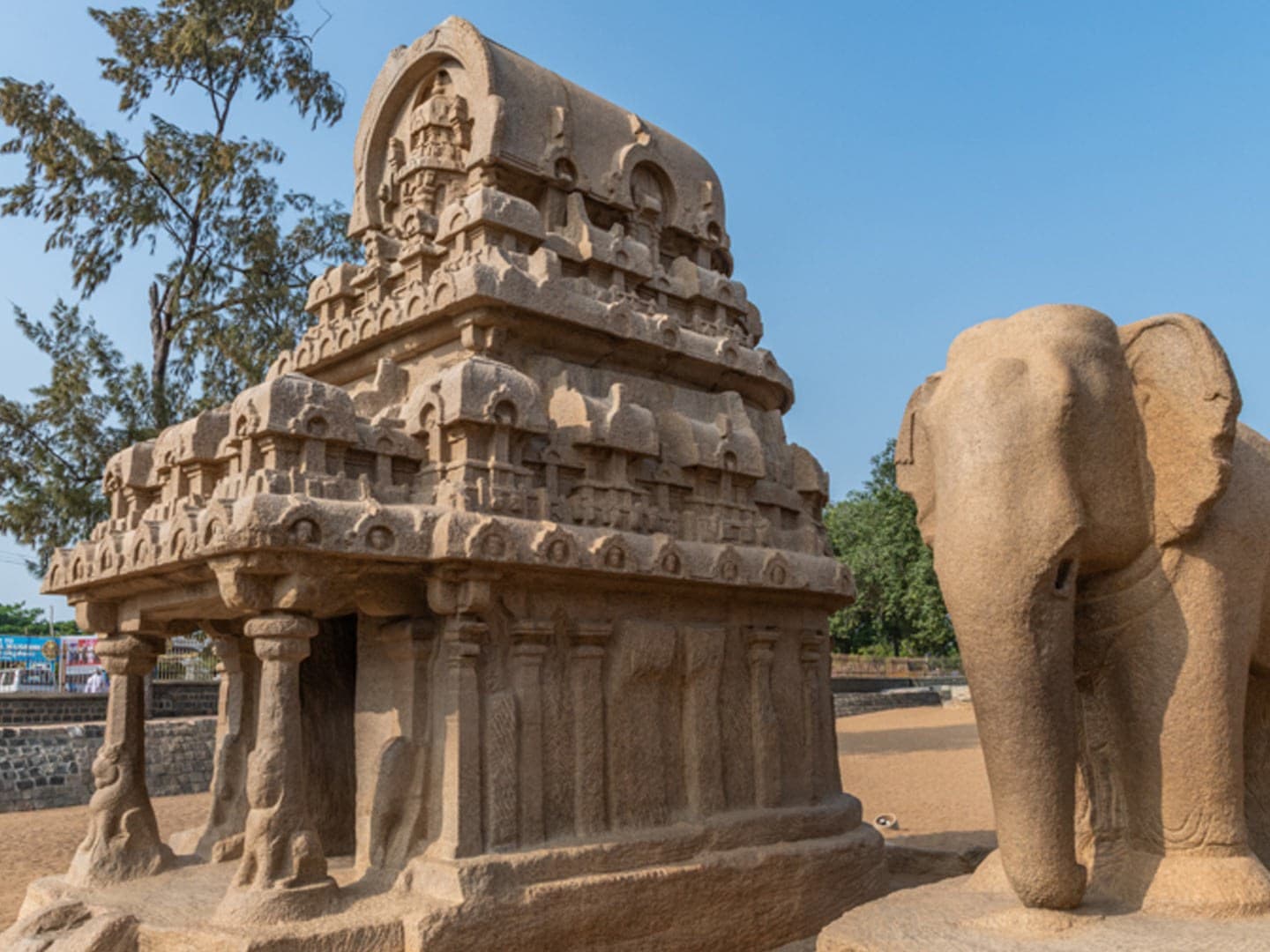 A monolithic chariot-shaped shrine of the Pancha Rathas beside the life-size carved stone elephant at Mamallapuram.