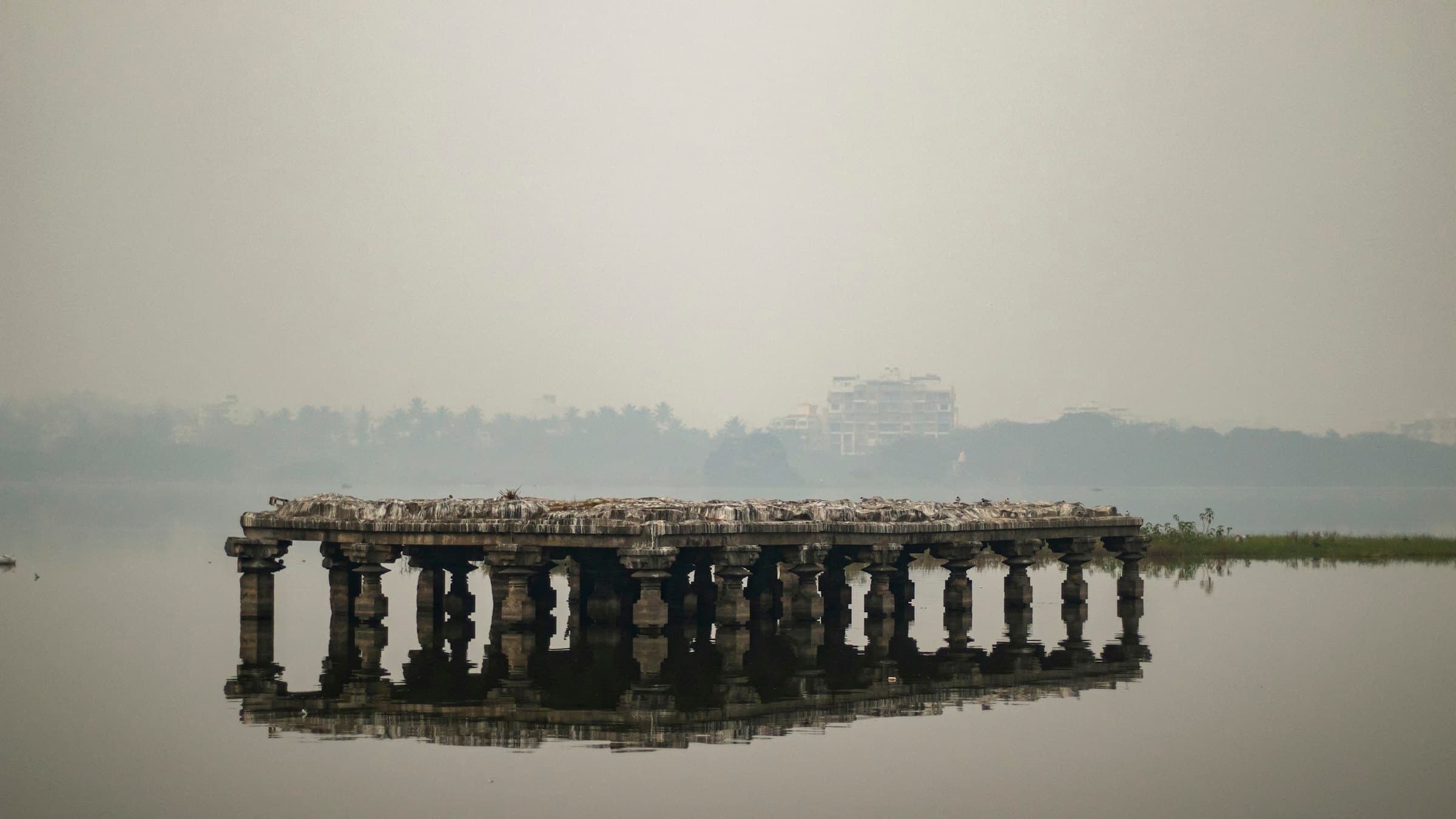 A lake with a pier and city buildings in Kolhapur, Maharashtra