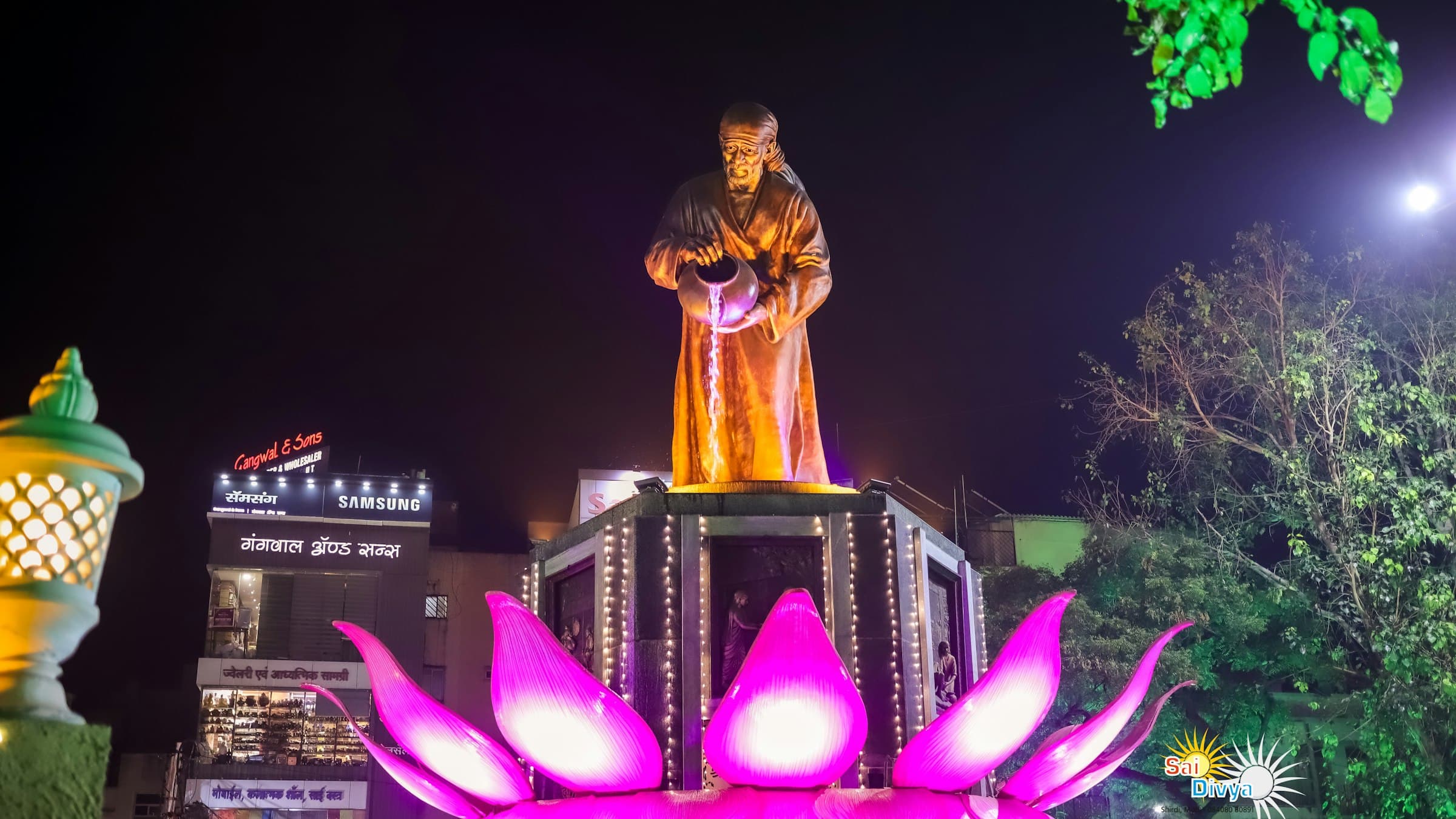 A statue of a standing figure beneath the moon at night in Shirdi, Maharashtra