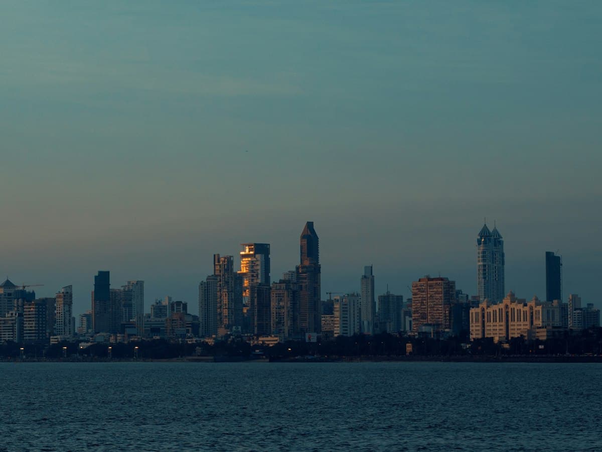 The Mumbai skyline across the water from Marine Drive under a sunset-toned sky