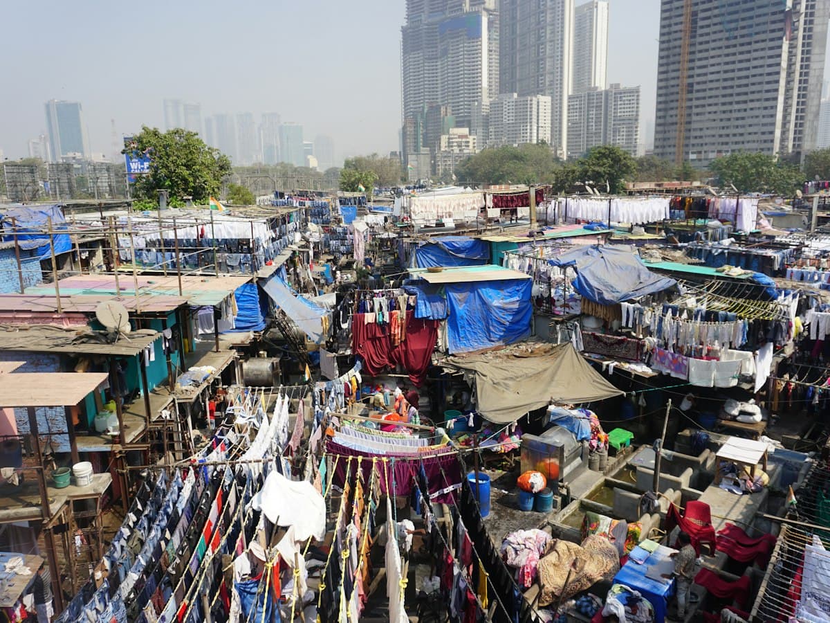 Rows of laundry drying beside the washing pens of Dhobi Ghat with city towers behind, Mumbai