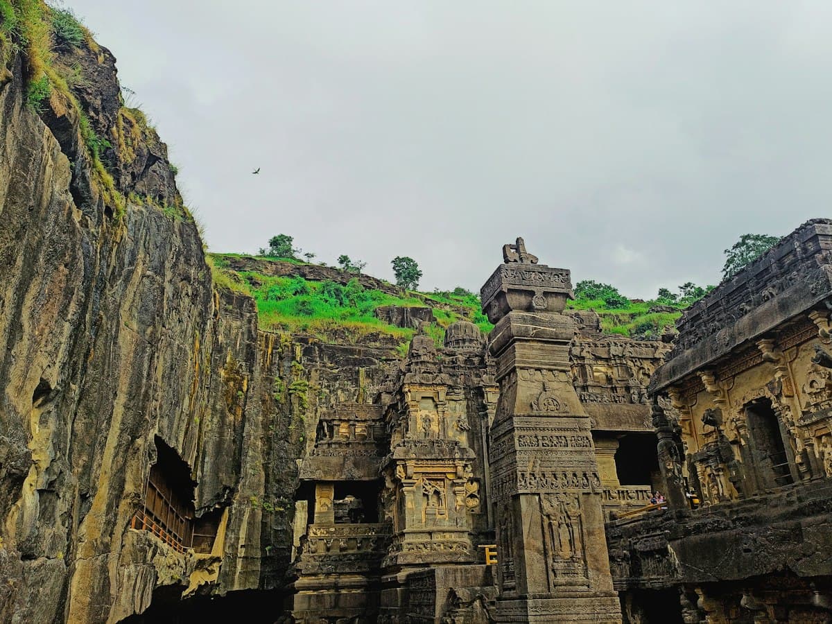 Ancient rock-cut stone structures of the Ellora Caves against a green hill near Aurangabad