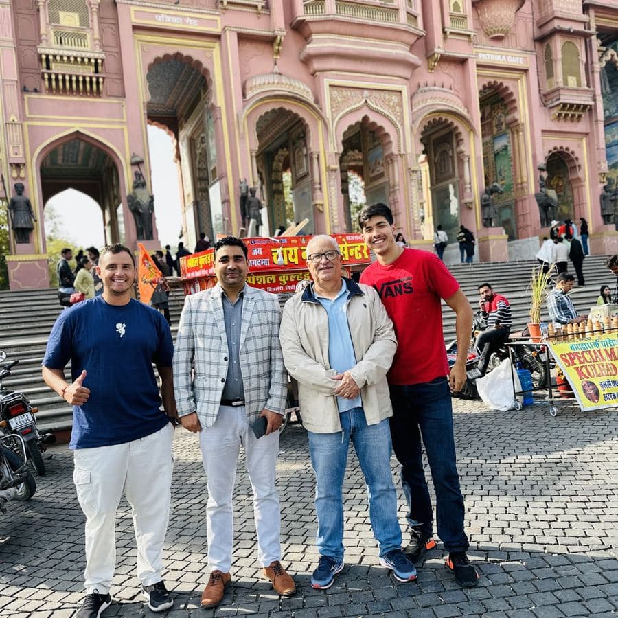 Four guests posing together in front of a pink sandstone city gate in Jaipur
