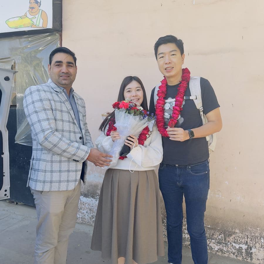 A tour guide presenting flowers to two guests on the street