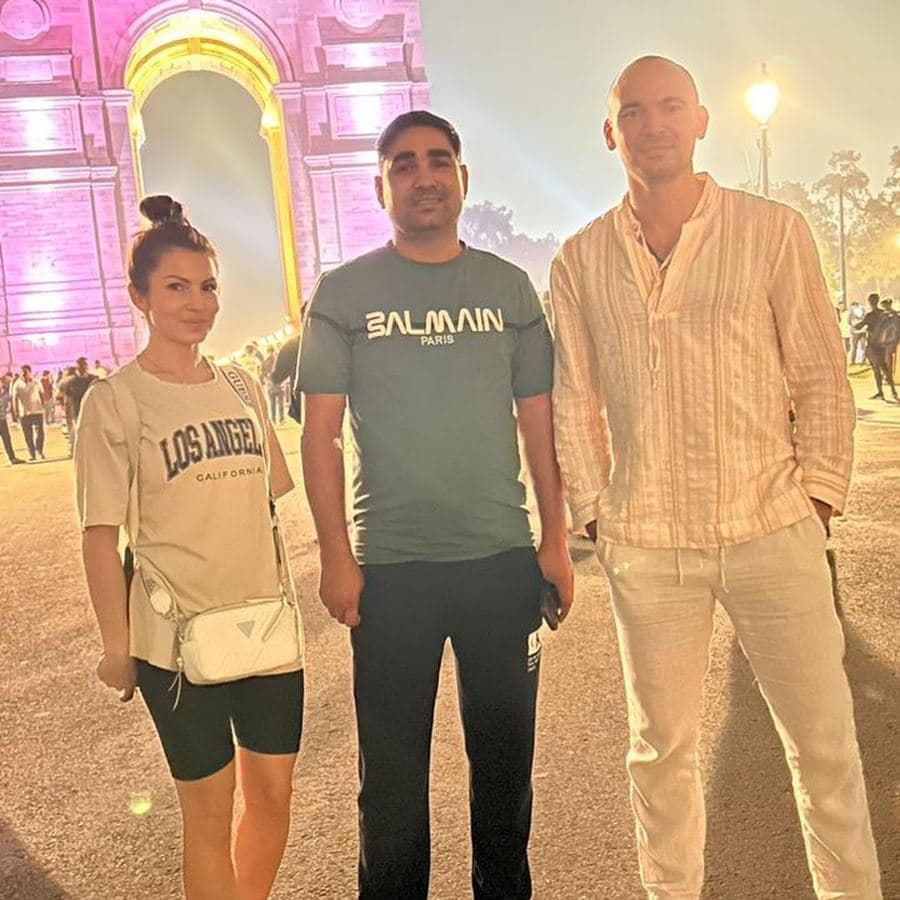 Three guests posing at night in front of an illuminated monument gateway