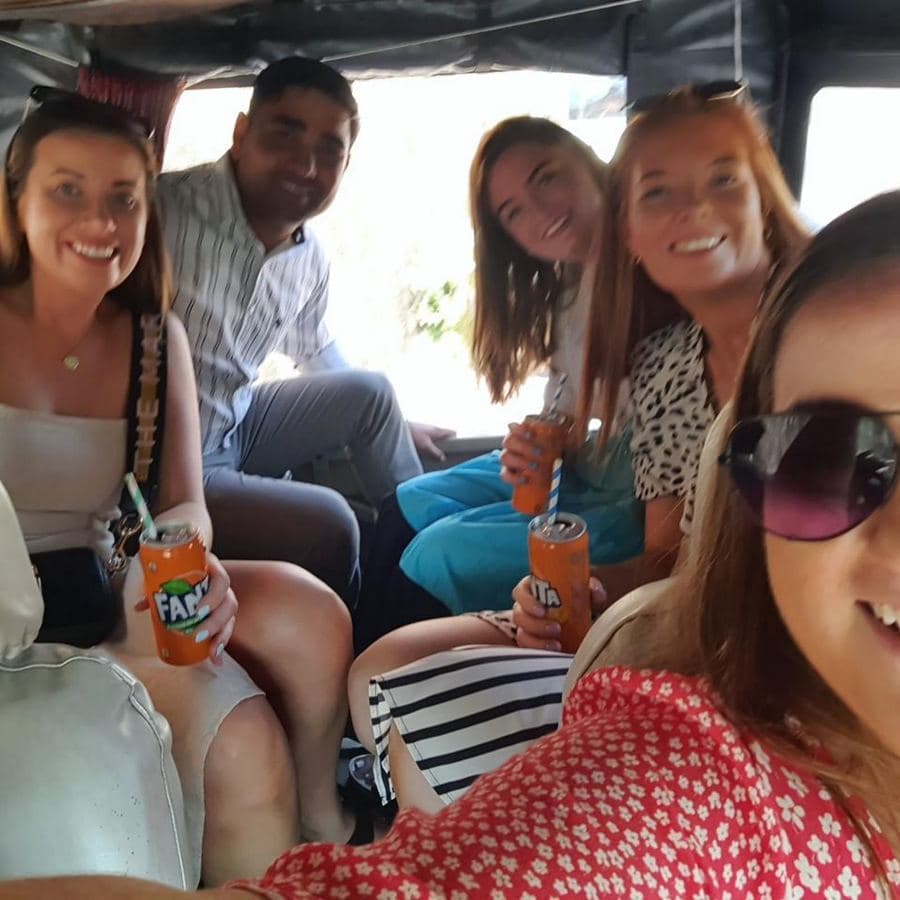 A group of guests smiling for a candid selfie inside an open-air safari vehicle