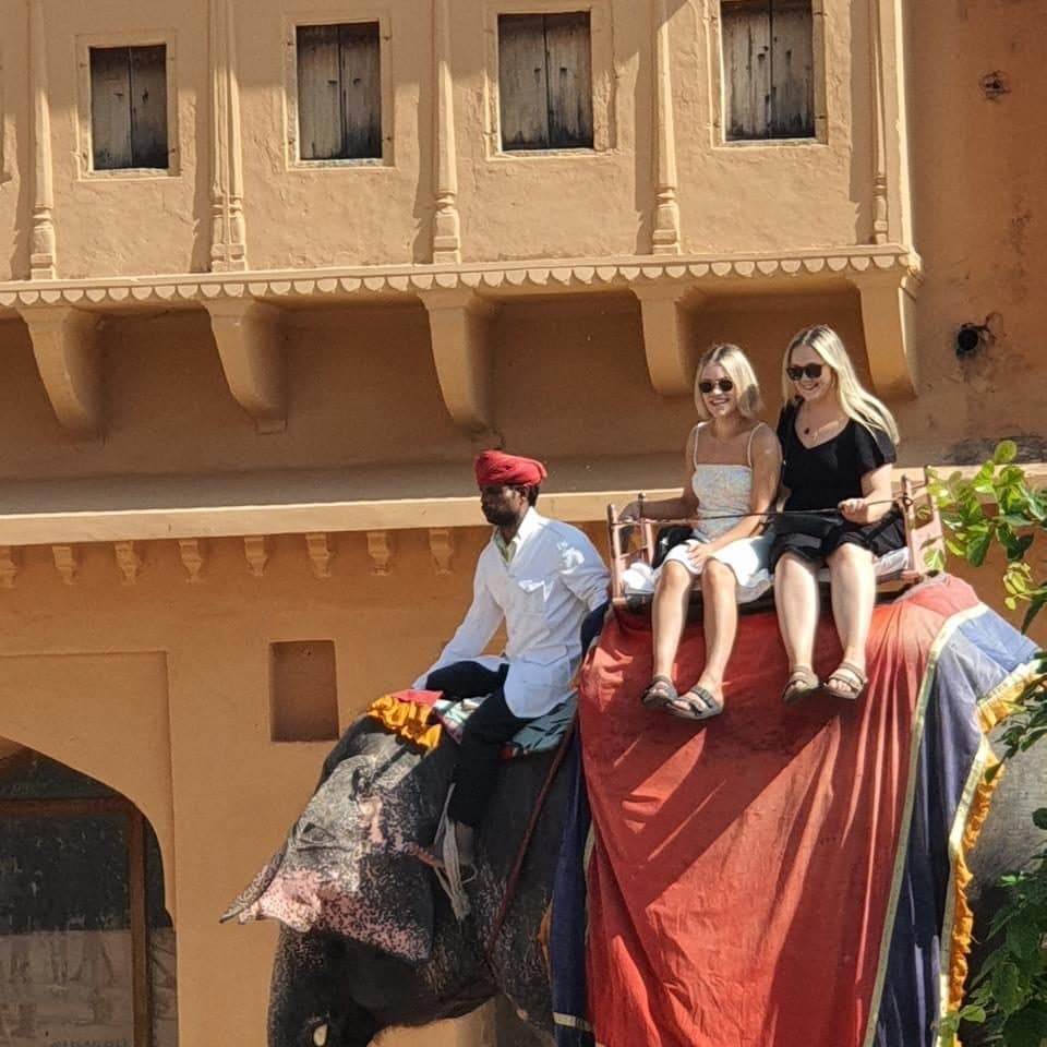 Guests riding a caparisoned elephant with its mahout up to Amber Fort