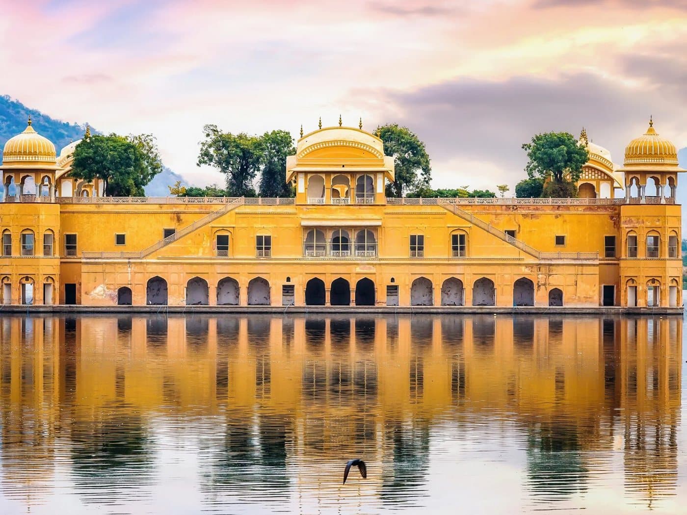 The Jal Mahal water palace sitting mid-lake at Jaipur under a pink dusk sky