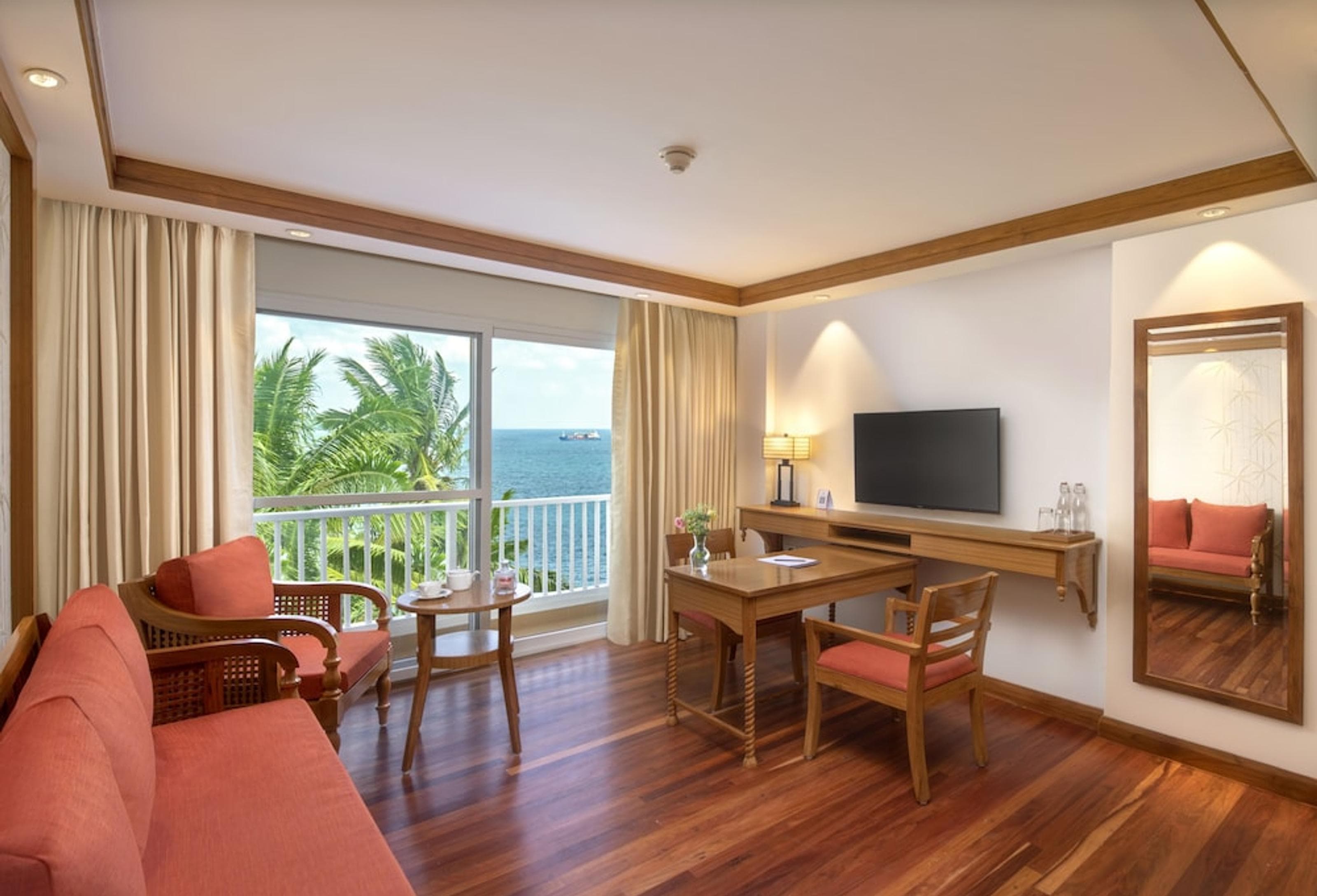 Living area of an Executive Suite at Welcomhotel Bay Island with a sea view through palm trees