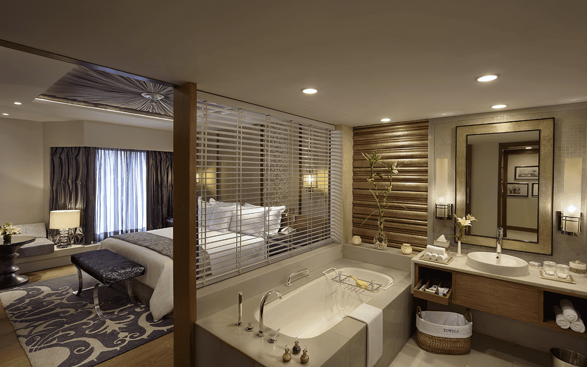 The bedroom of a Royal Mughal Suite at ITC Mughal Agra, seen through a window from the adjoining bathroom