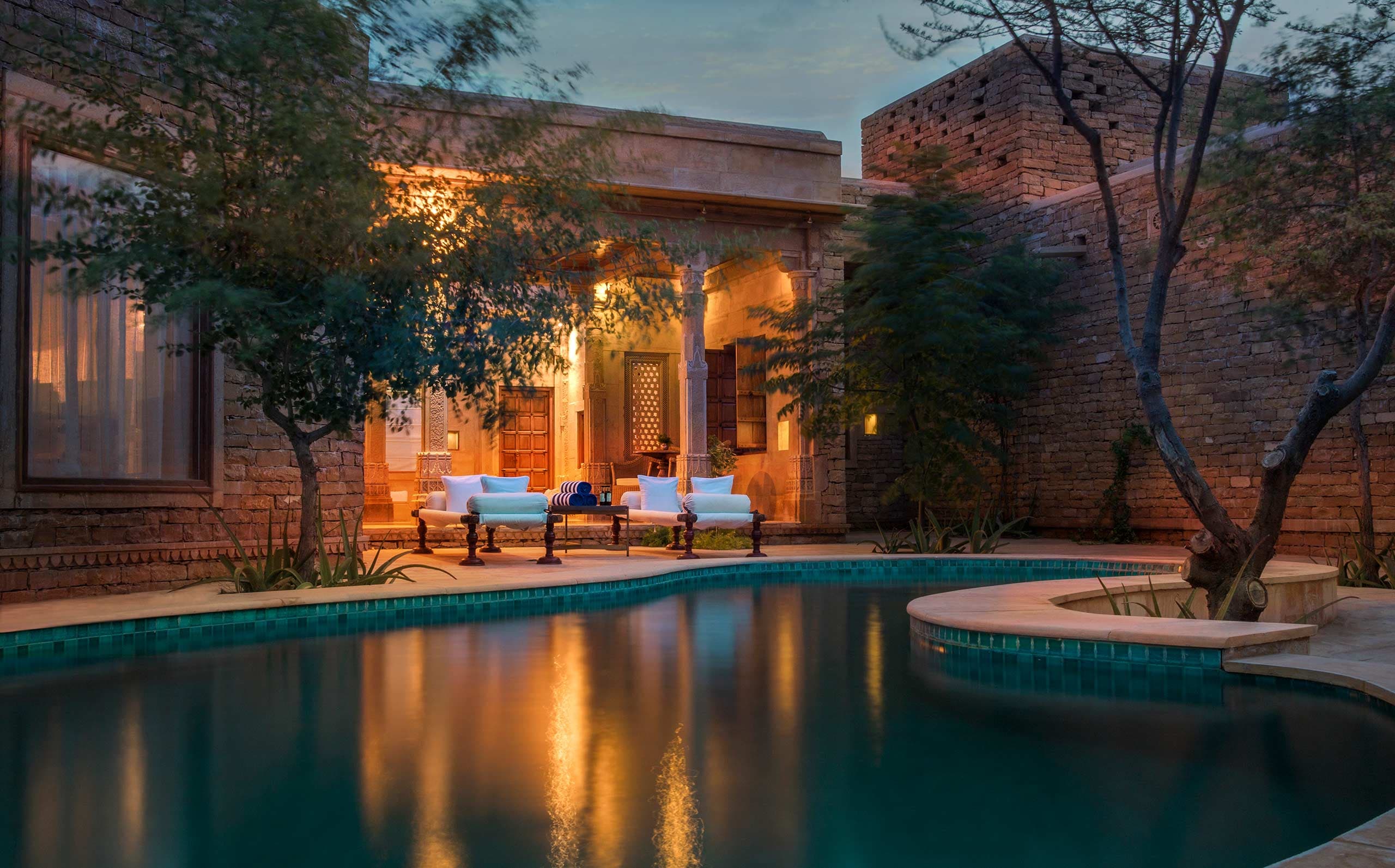 Suryagarh's Jaisalmer Haveli suite bedroom with a private balcony opening onto the desert building beyond