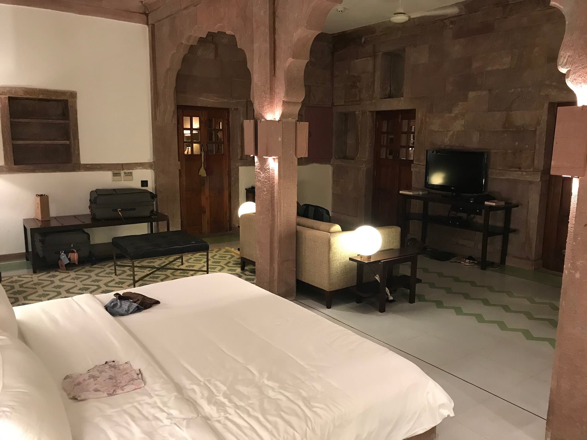 RAAS Jodhpur Heritage Suite interior with exposed sandstone arches, a sitting area, and stone-carved wall niches