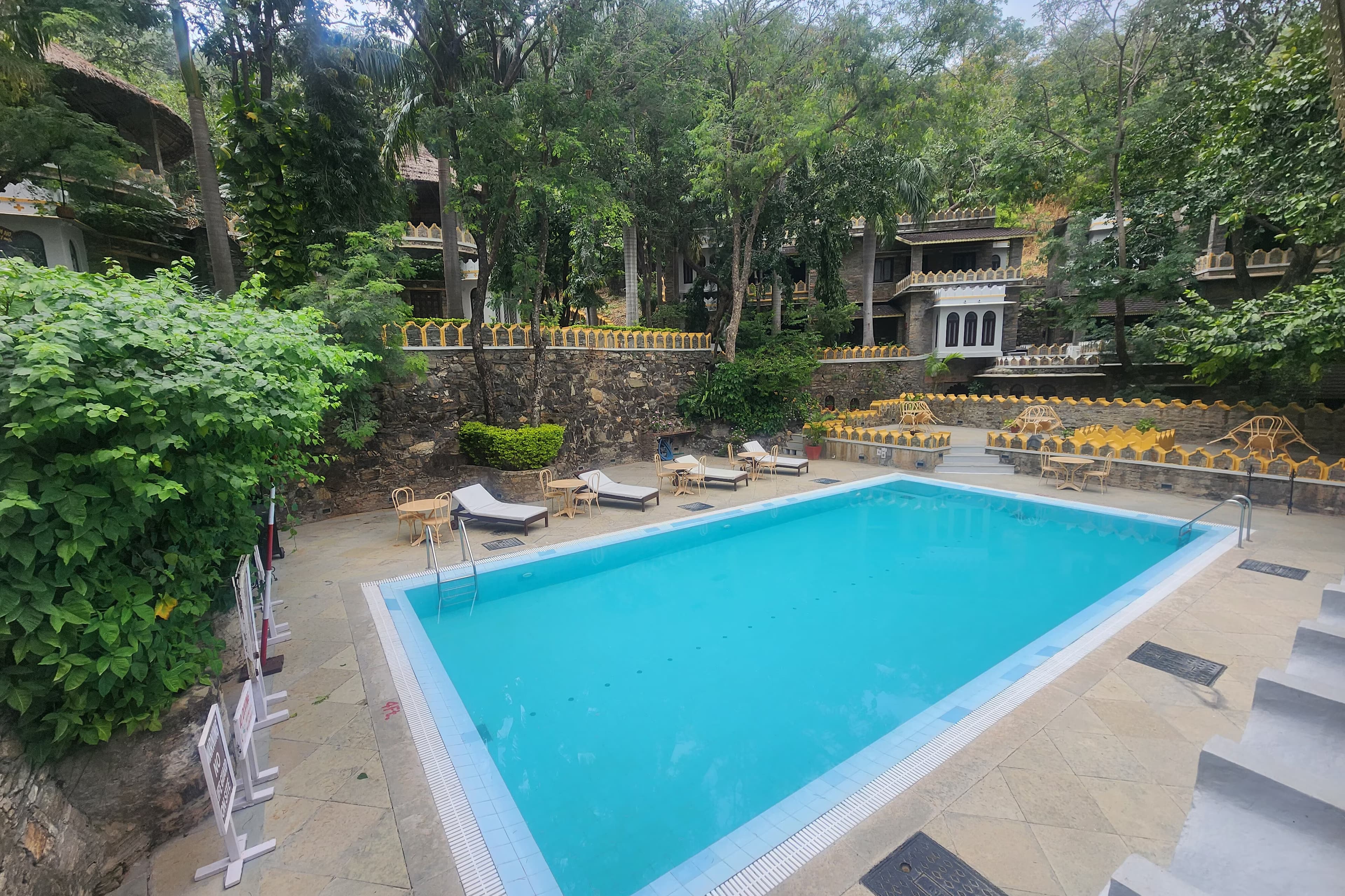 The Aodhi's outdoor swimming pool by day, framed by its stone terraces and the wooded hills behind