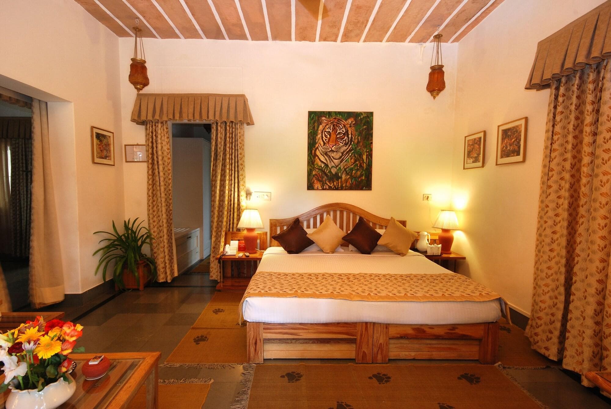 The Aodhi's Heritage Suite bedroom with a carved wooden bed, tiger artwork, and hanging brass lanterns