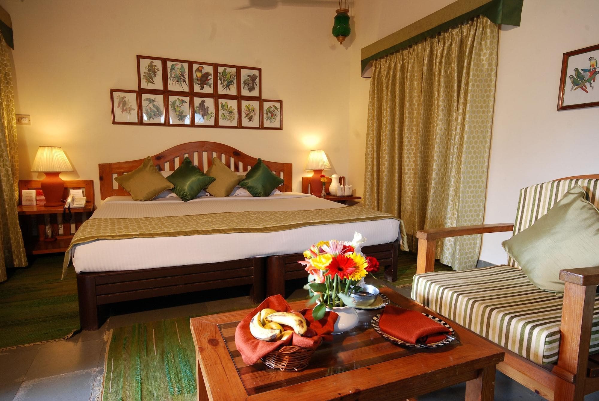 The Aodhi's Deluxe Room with twin beds, parrot-motif artwork, and a small seating table by the window