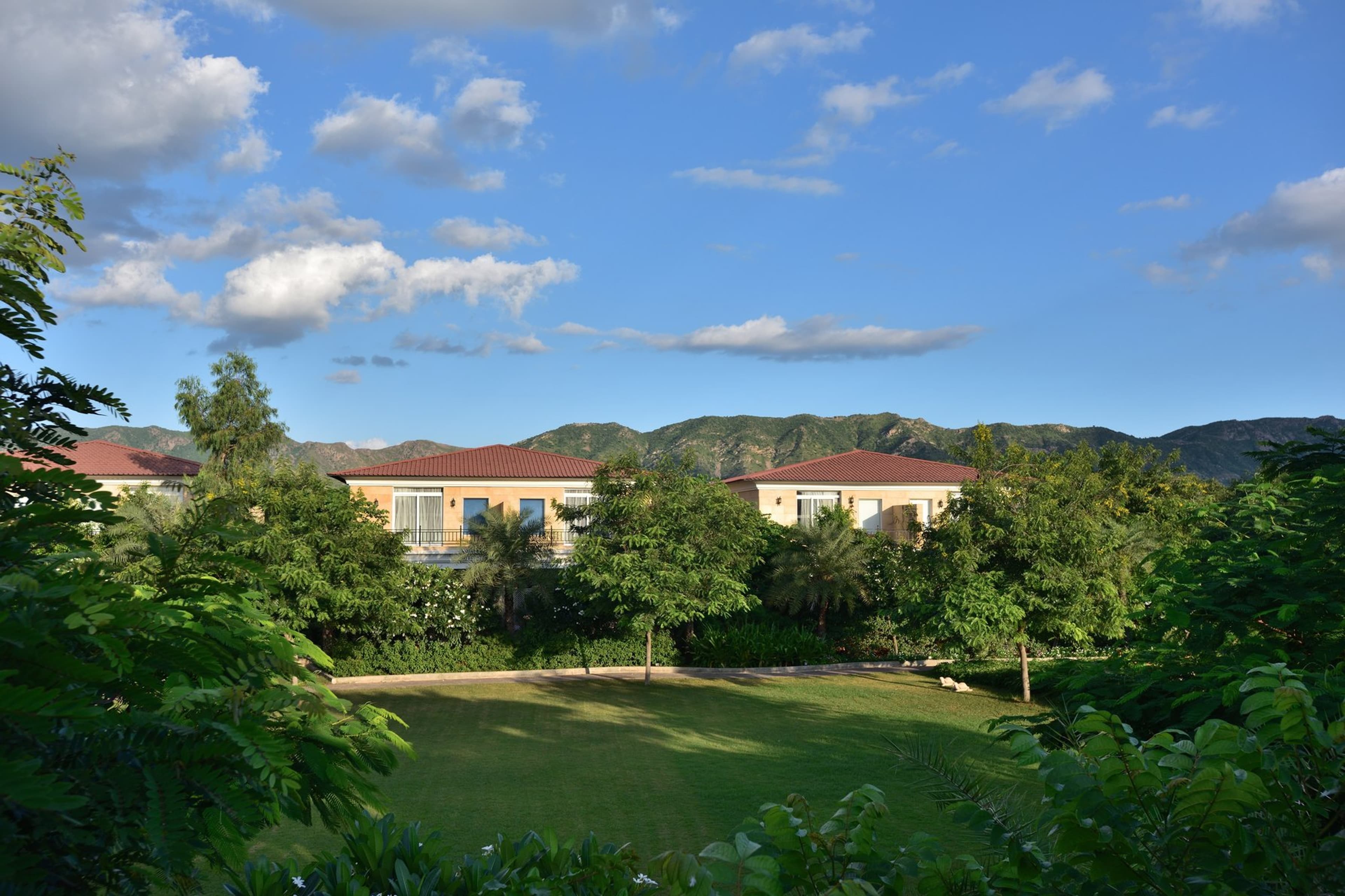 The Westin Pushkar Resort & Spa's tile-roofed guest villas set among gardens with the Aravalli hills in the distance