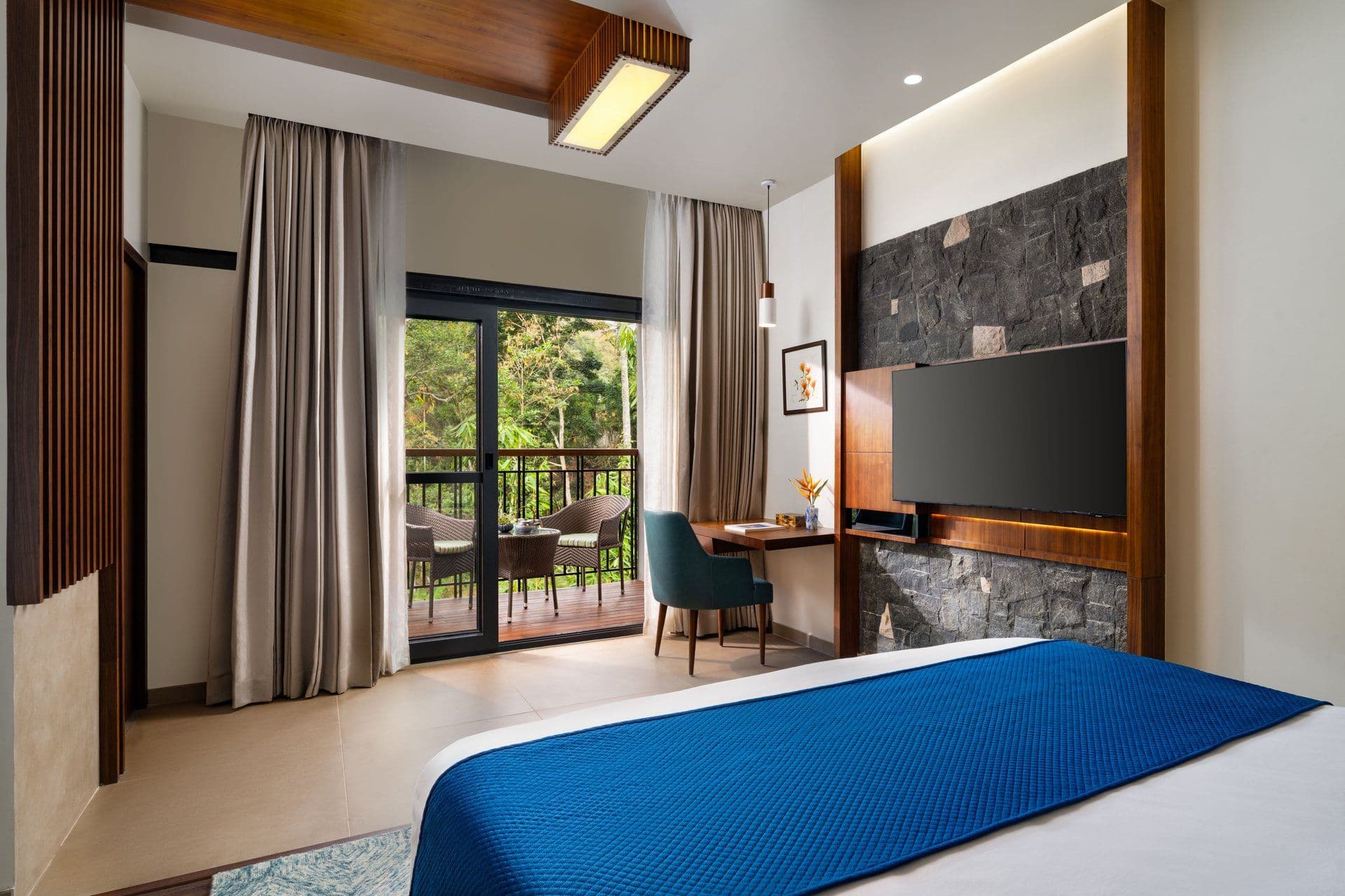 A Deluxe Room with Balcony at Scenic, Munnar, with a large bed and doors opening to the balcony