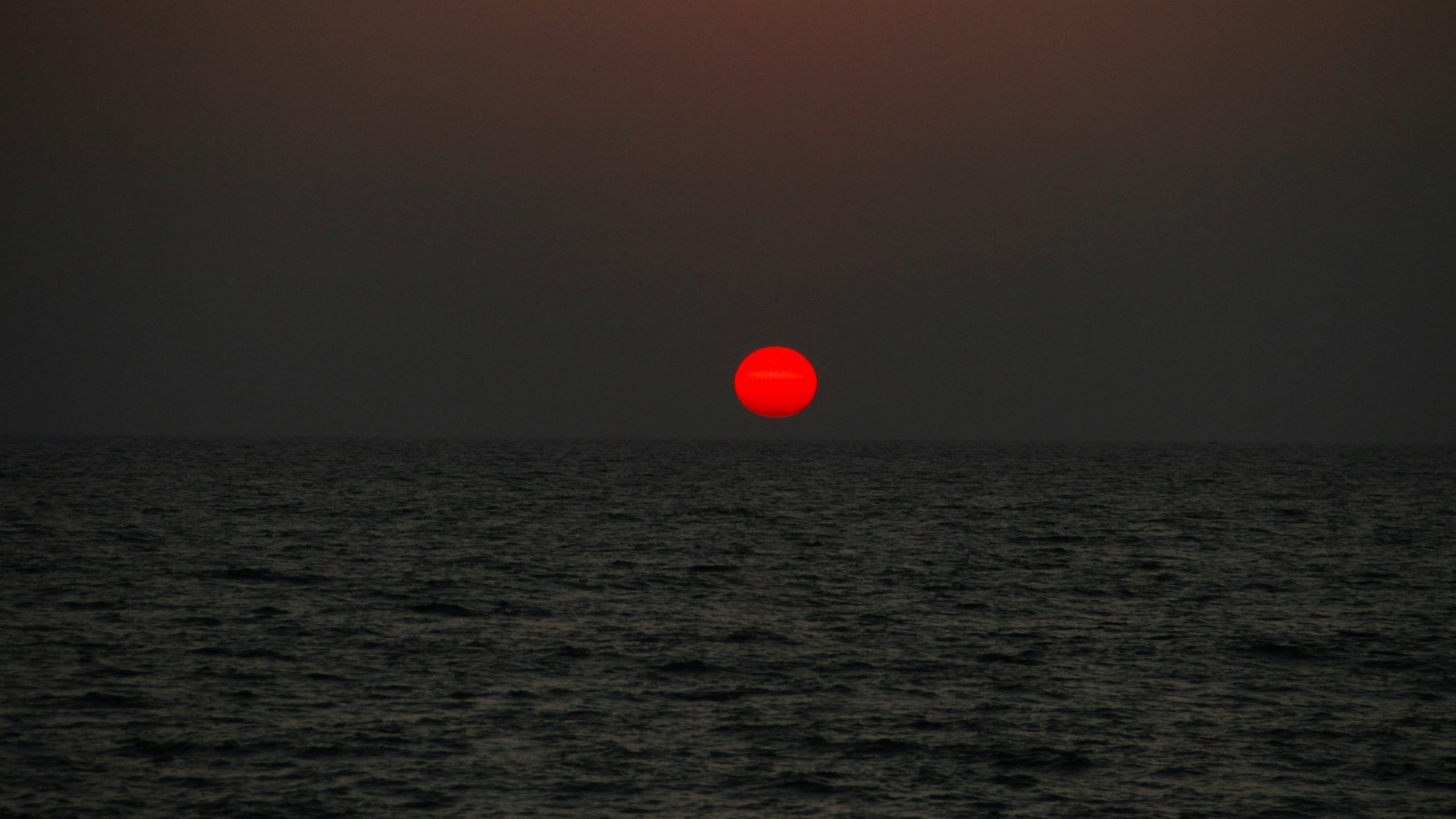 The sun setting over the Arabian Sea under a cloudy sky