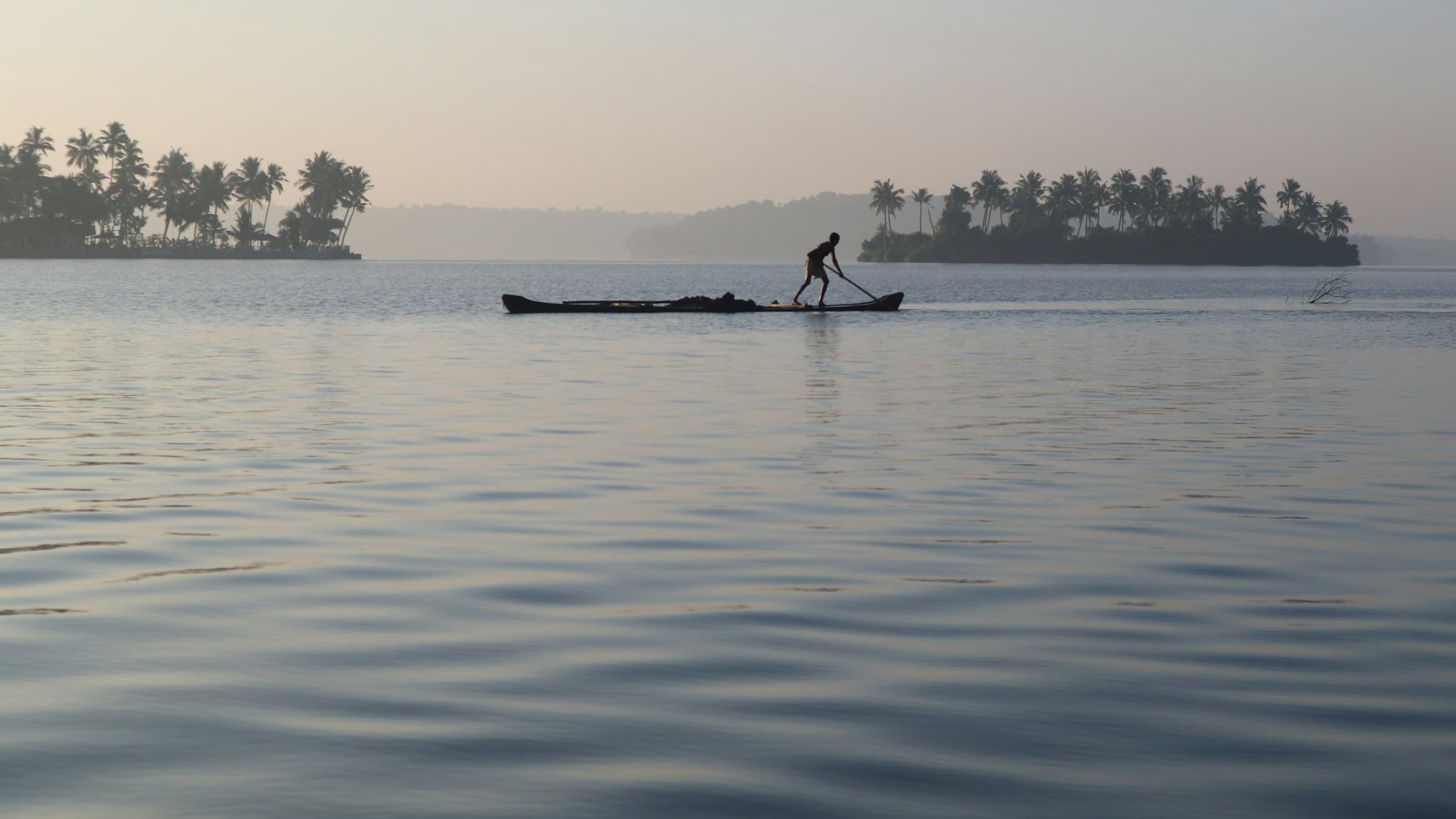 Two people on a boat on the Kerala backwaters at first light