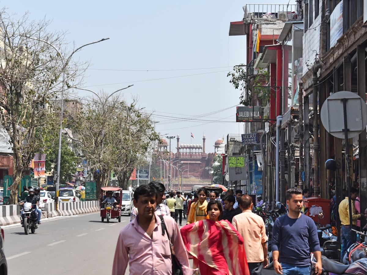 A busy lane in Old Delhi with pedestrians, cycle-rickshaws and shopfronts