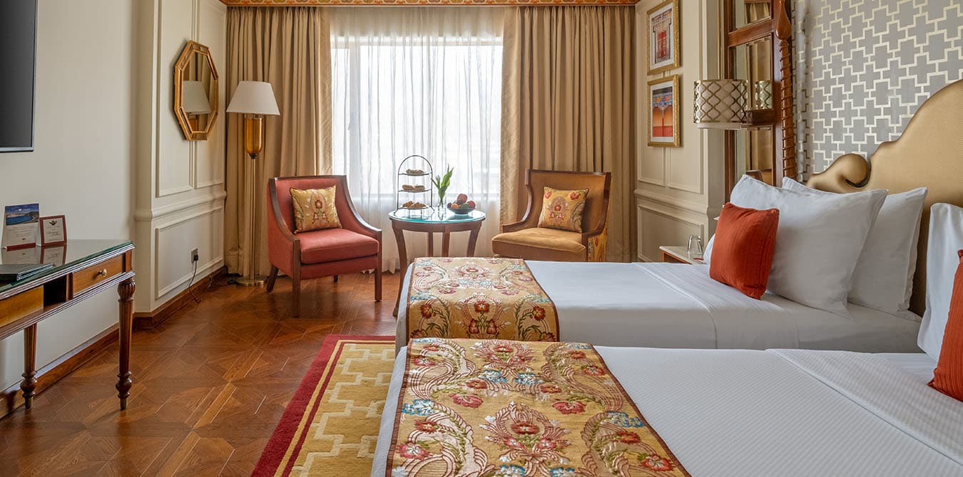 Luxury Room (the hotel's deluxe category) at The Grand Dragon Ladakh with twin beds, two armchairs and a curtained window