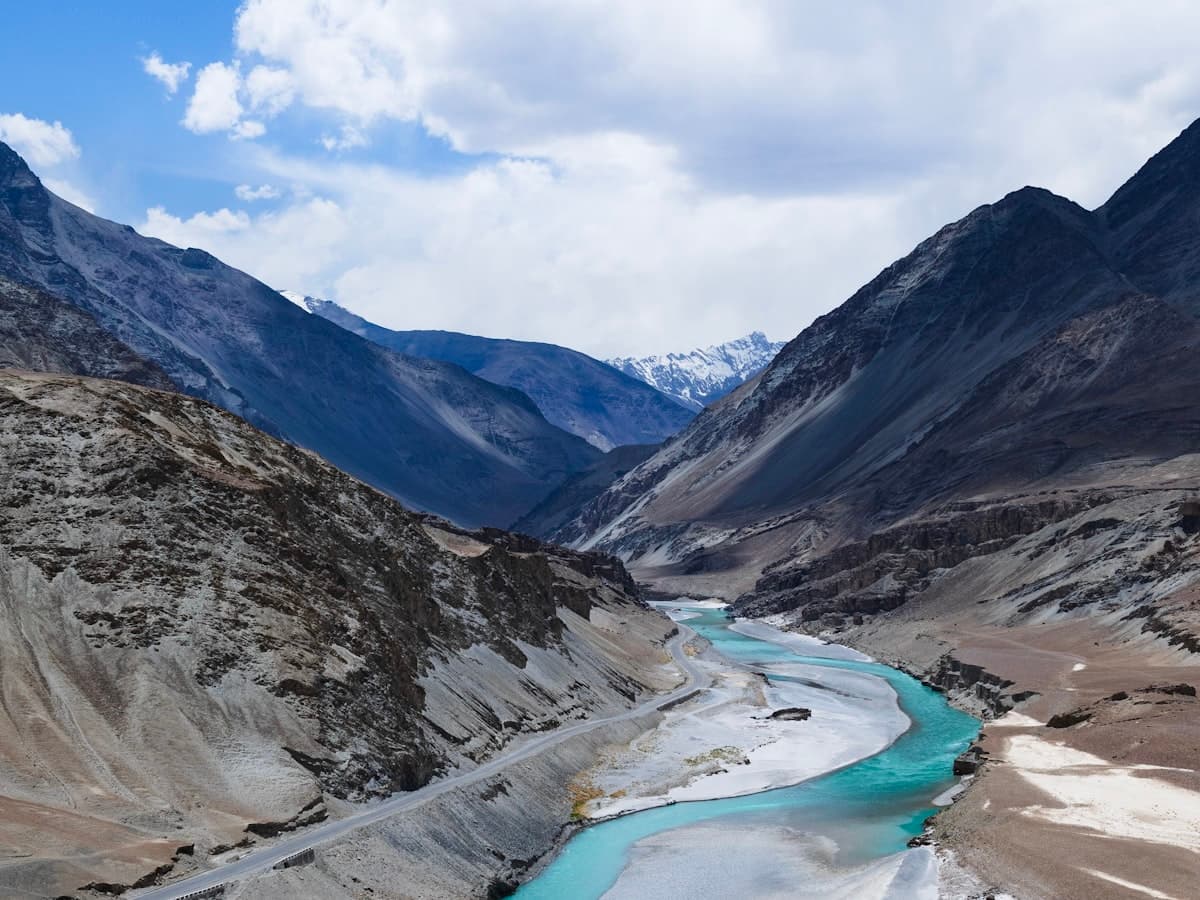 The Sangam confluence in the Sham valley, where the muddy Zanskar meets the turquoise Indus between bare desert mountains.