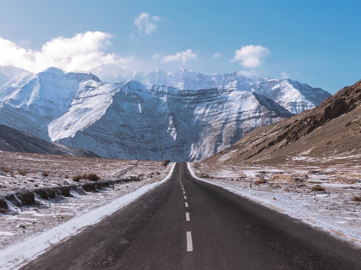 An empty ribbon of road running out of Leh along the Indus valley floor, the bare mountain range framing a last look at Ladakh.