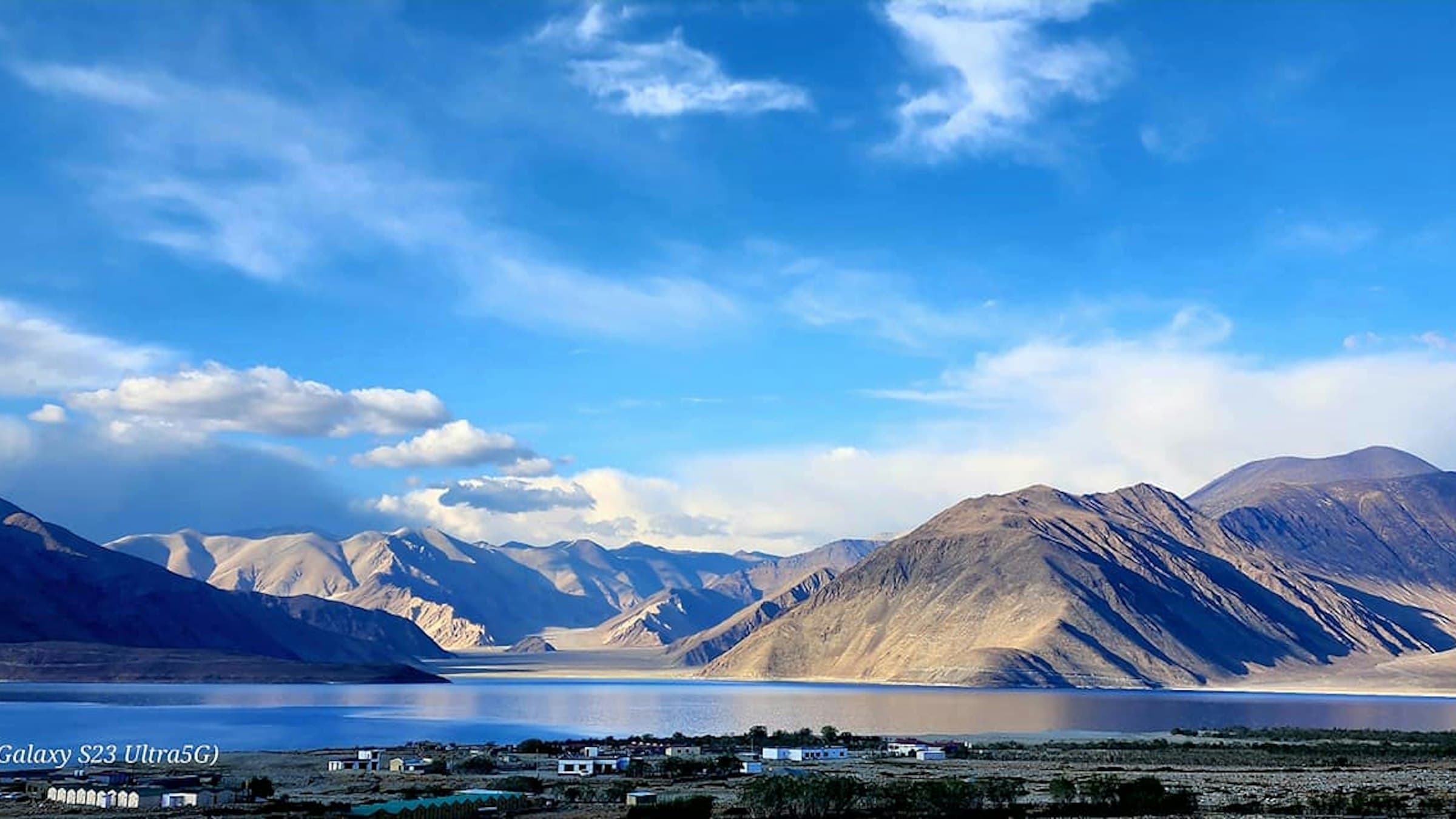 The electric-blue expanse of Pangong Tso ringed by snow-dusted mountains under a deep azure Ladakh sky.