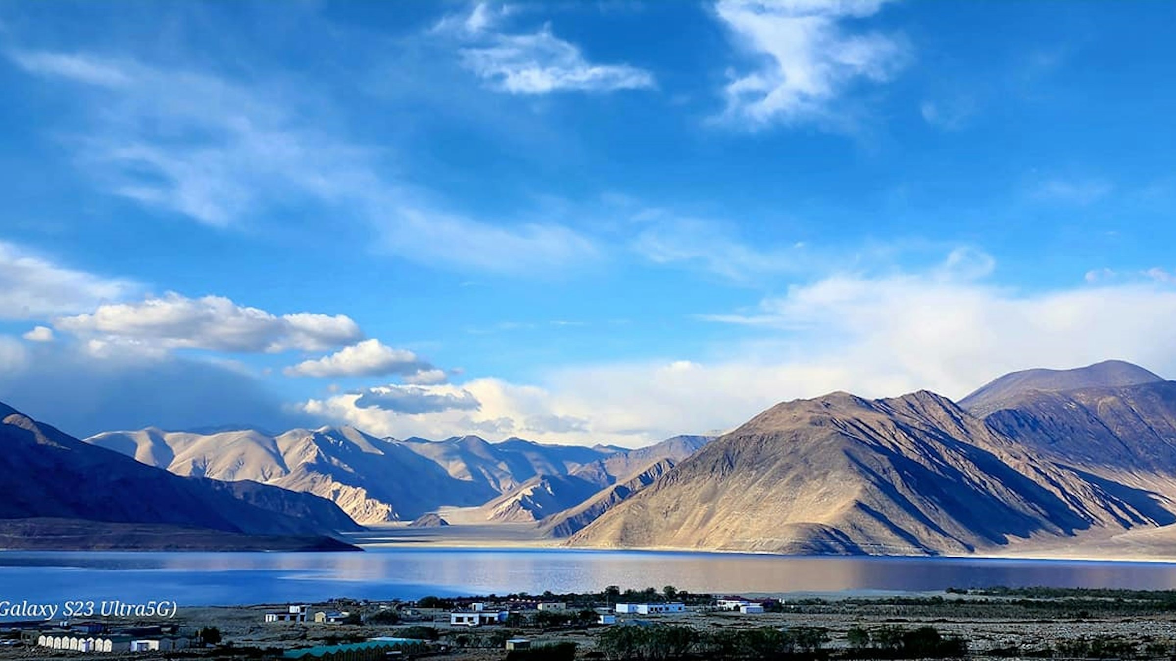 The electric-blue expanse of Pangong Tso ringed by snow-dusted mountains under a deep azure Ladakh sky.