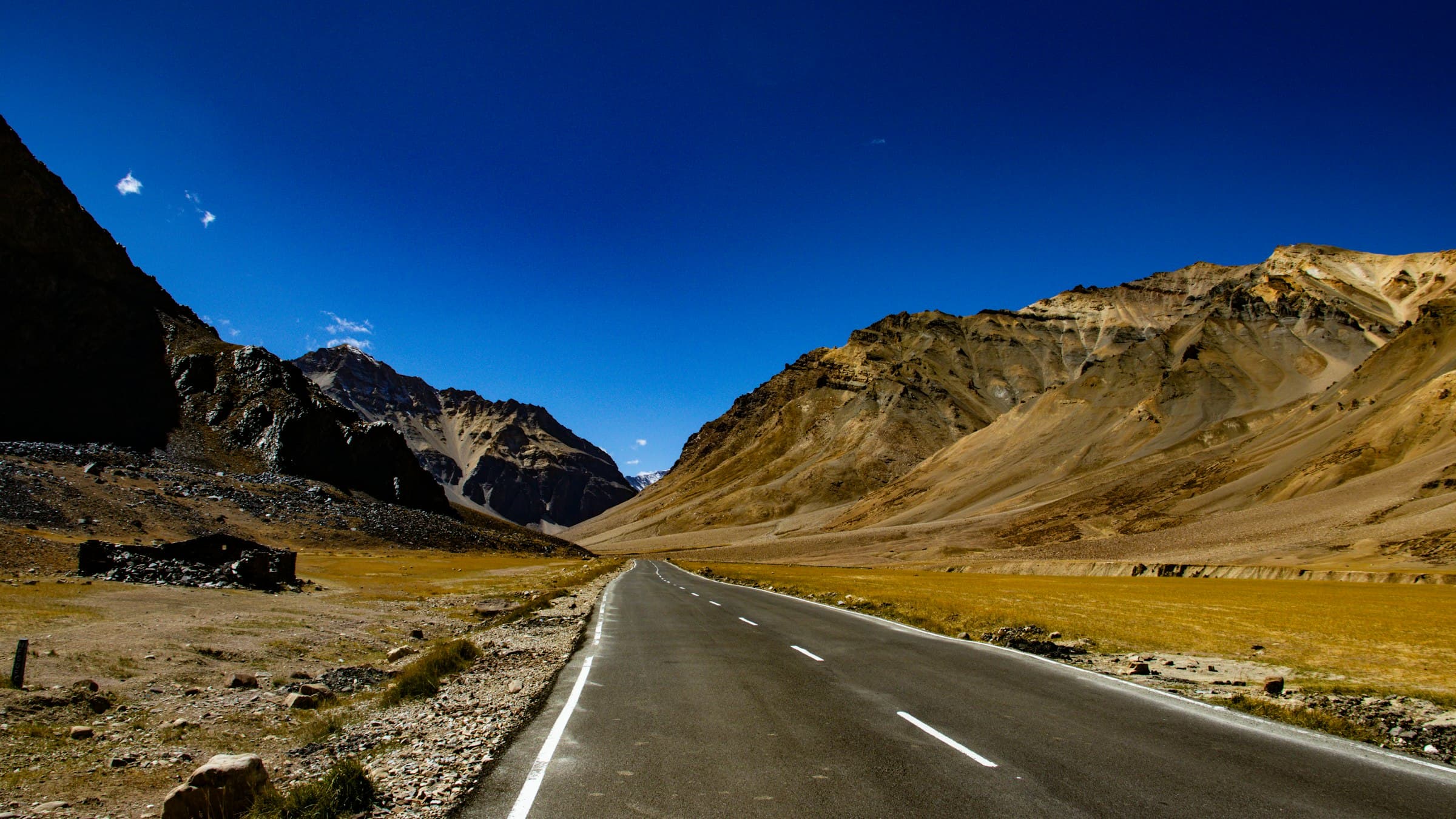 A lone road runs dead straight into a vast amphitheatre of bare Ladakh mountains, the scale of the high desert dwarfing everything on it.