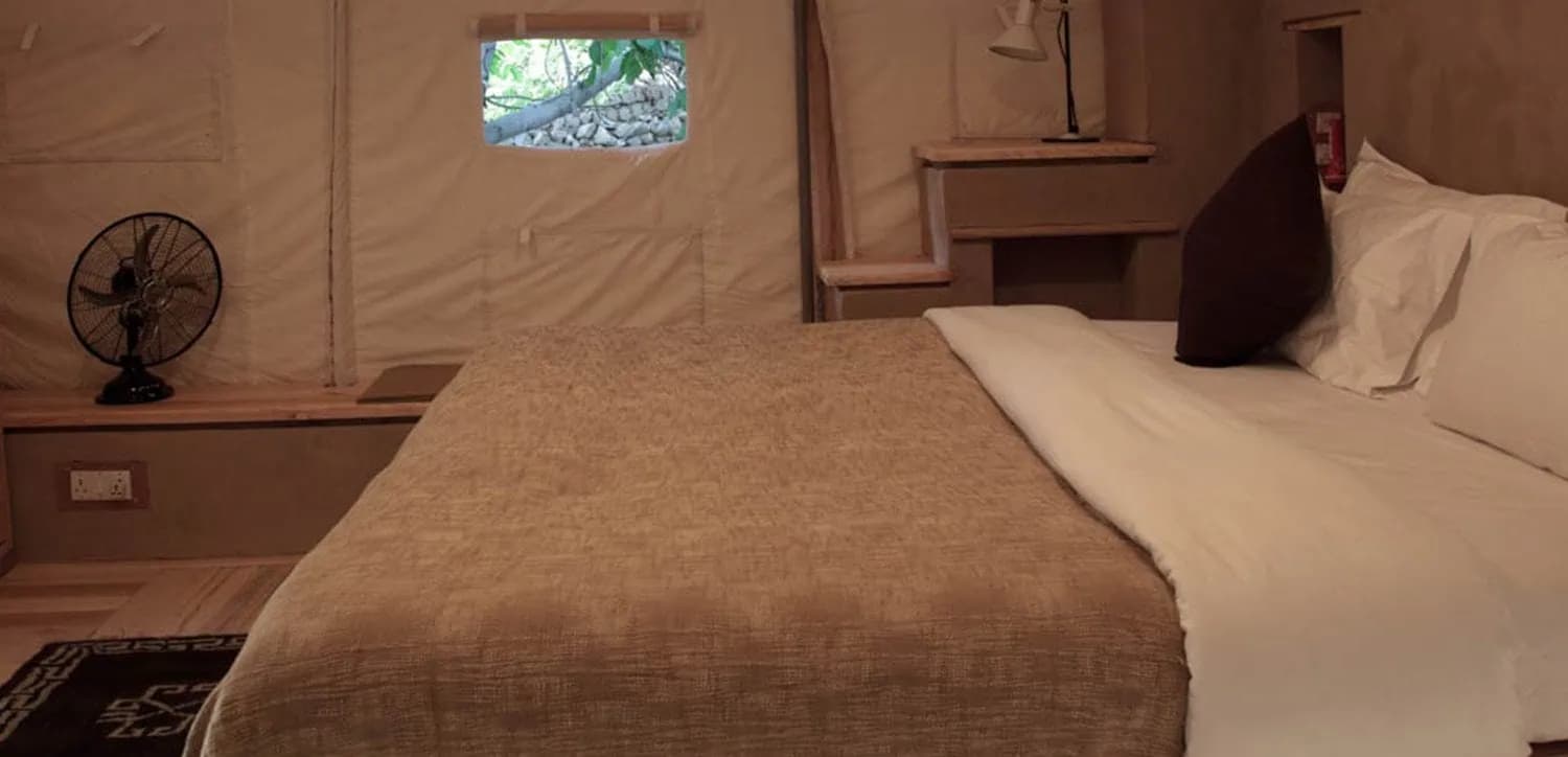 Inside a luxury garden tent at Nimmu House, with a double bed, rugs and canvas walls, pitched in the orchard