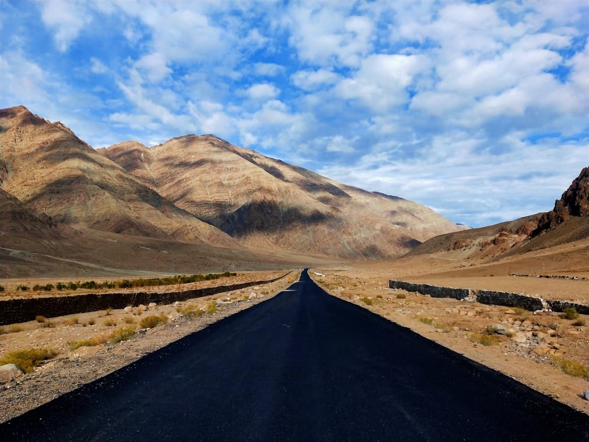 An empty ribbon of tarmac unspools west across the high desert floor below Ladakh's bare, wind-scoured ridgelines.