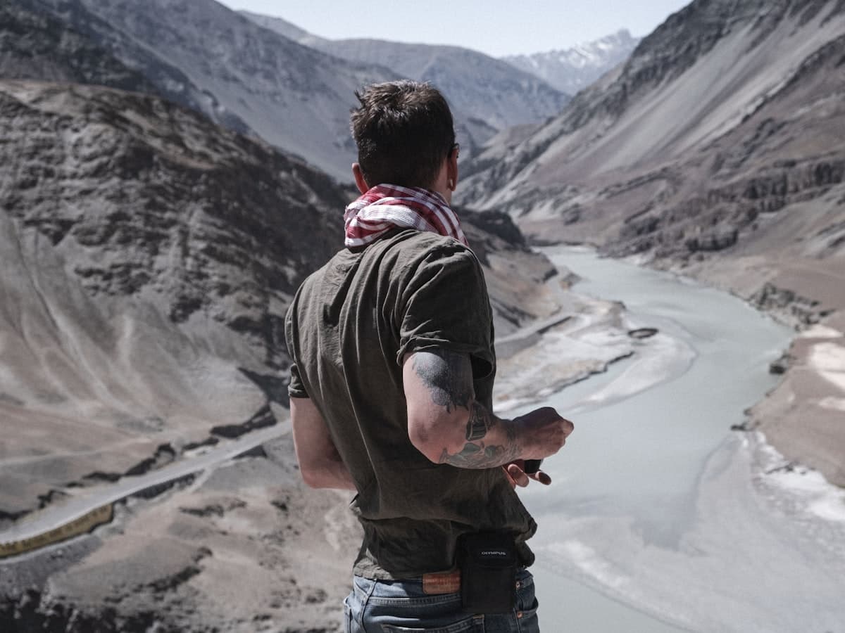 A traveller stands on a bluff where a braided river cuts through bare Ladakhi mountains on the road back to Leh.